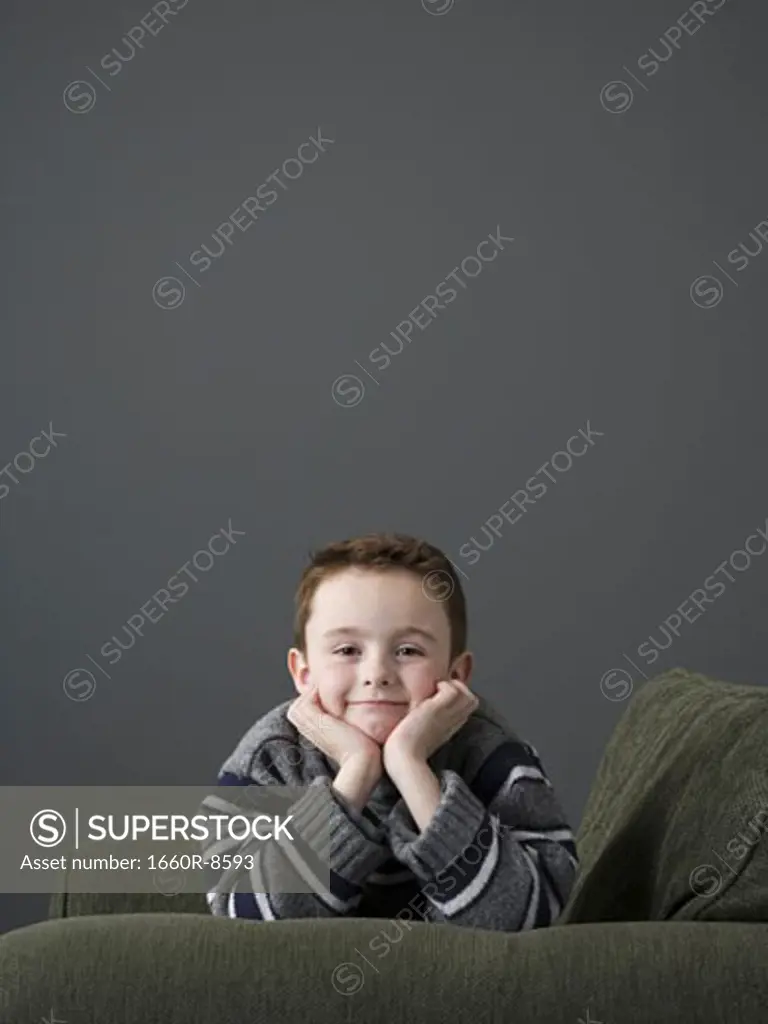 Portrait of a boy lying on a couch with his hand on his chin