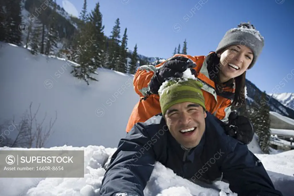 Portrait of woman sitting on a man's back in the snow