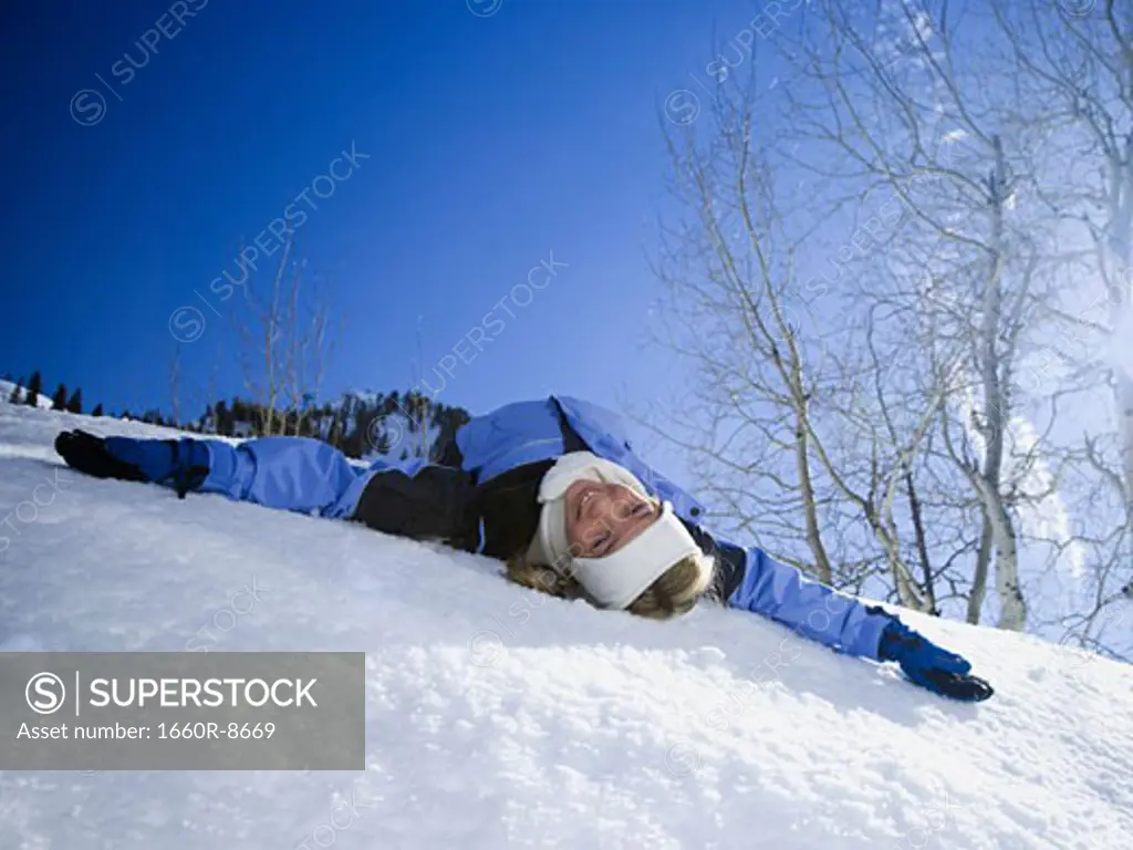 Portrait of a girl lying on snow with her arms outstretched