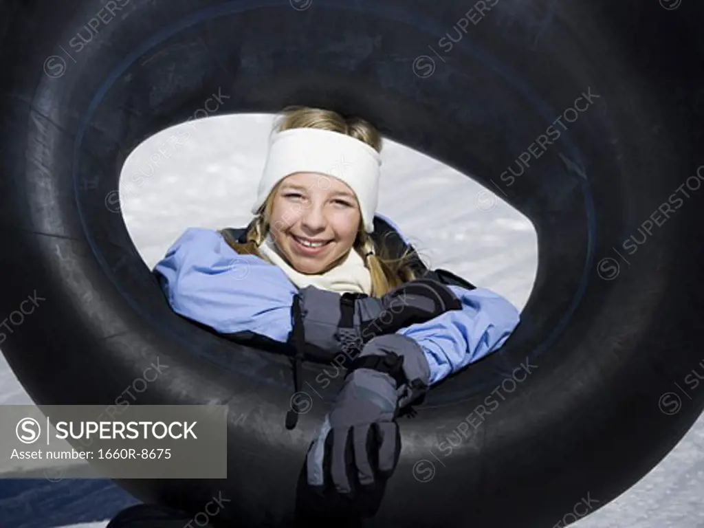 Portrait of a girl sitting on the snow with an inner tube