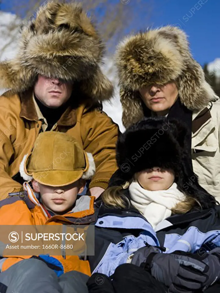 Close-up of parents and their children with hats covering their eyes