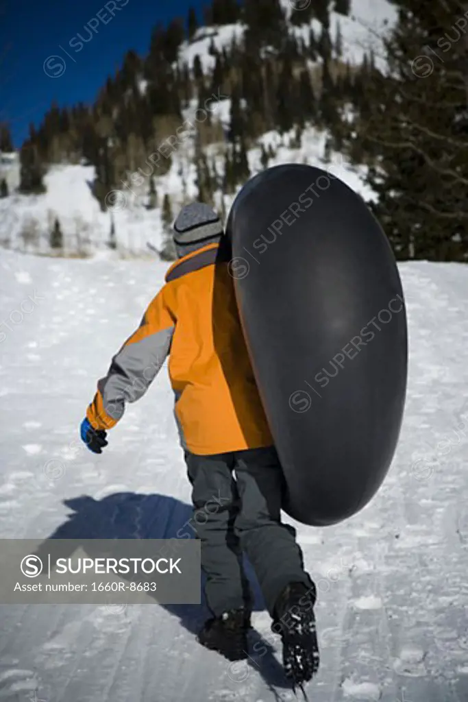 Rear view of a boy carrying an inner tube
