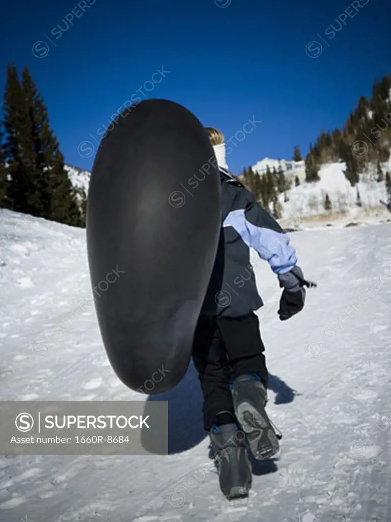 Rear view of a girl carrying an inner tube