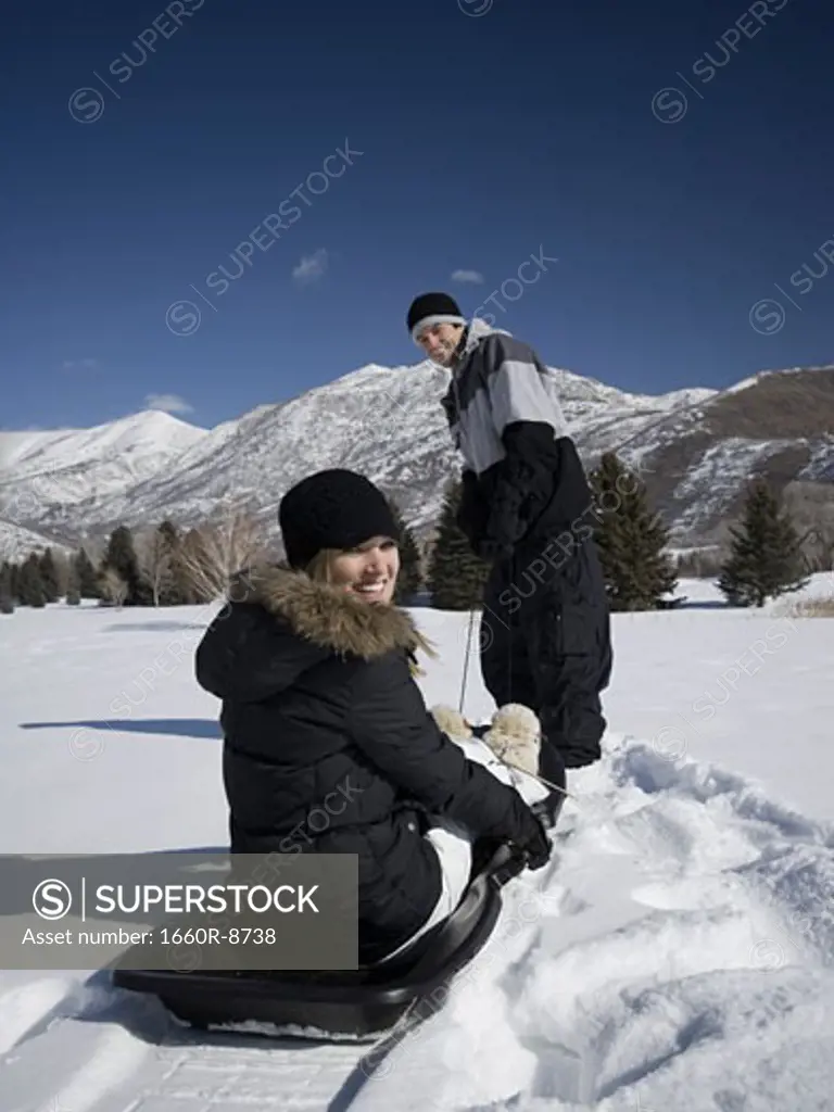 Young man pulling a young woman on a sleigh