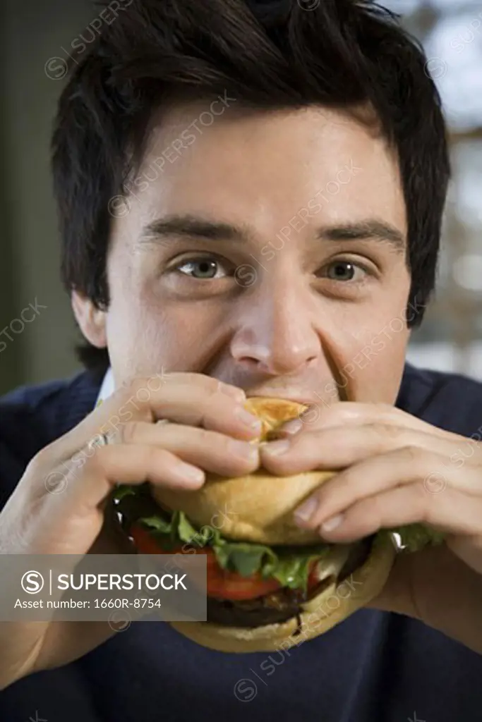 Portrait of a young man eating a hamburger