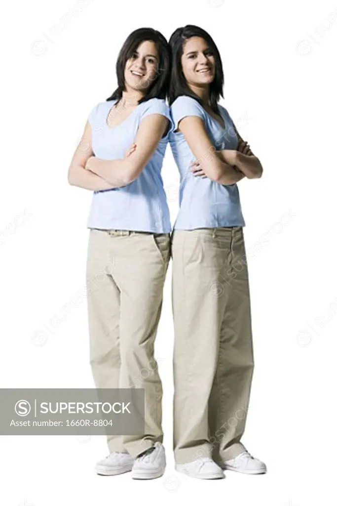 Portrait of two teenage girls standing back to back