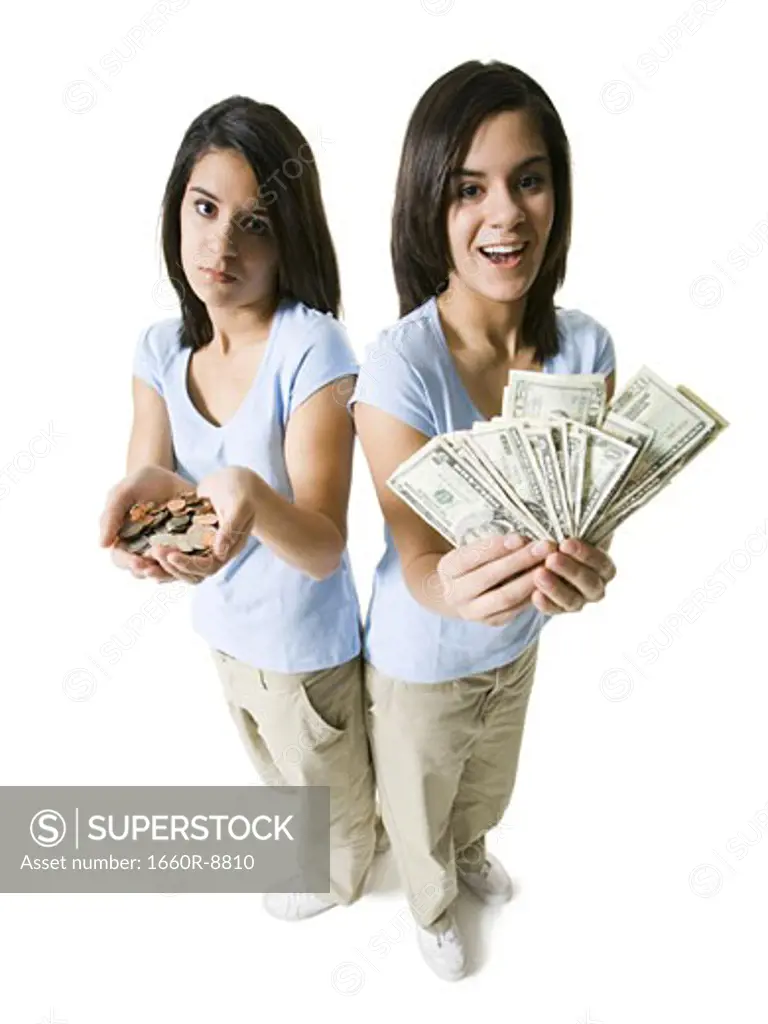 High angle view of two teenage girls holding American dollar bill and coins