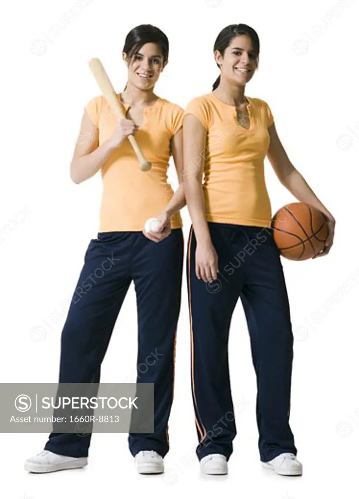 Portrait of two teenage girls holding a baseball bat and a basketball