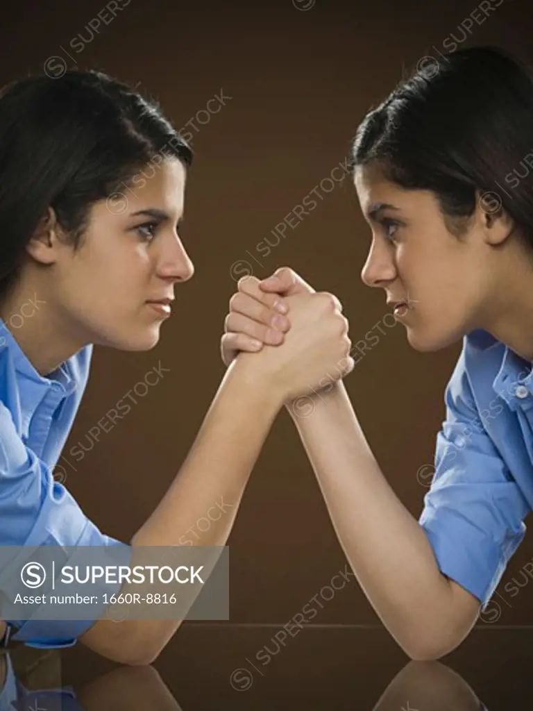 Profile of two teenage girls arm wrestling