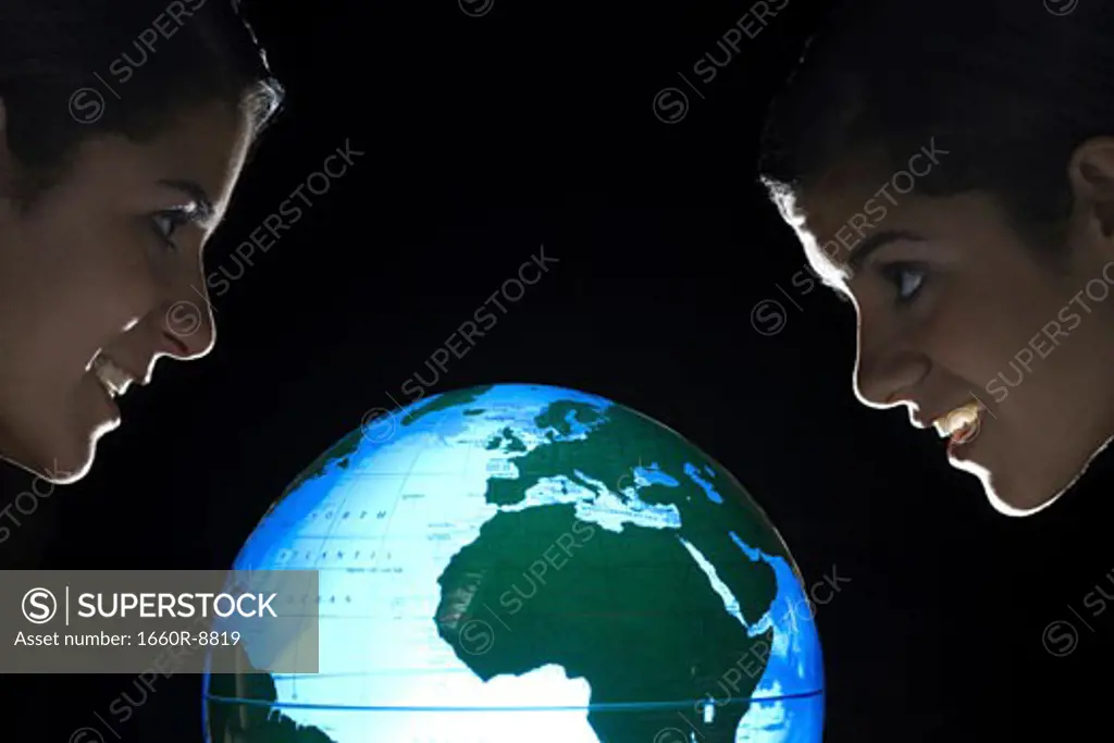 Side view of two teenage girls near a glowing globe