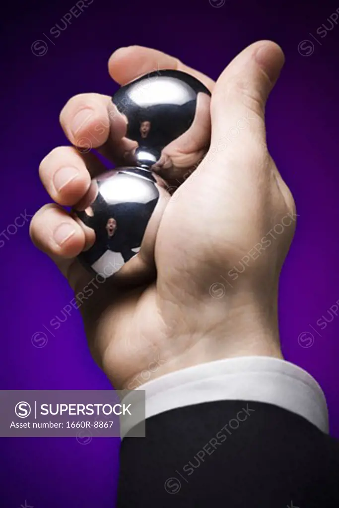 Close-up of a businessman's hand holding two metal balls