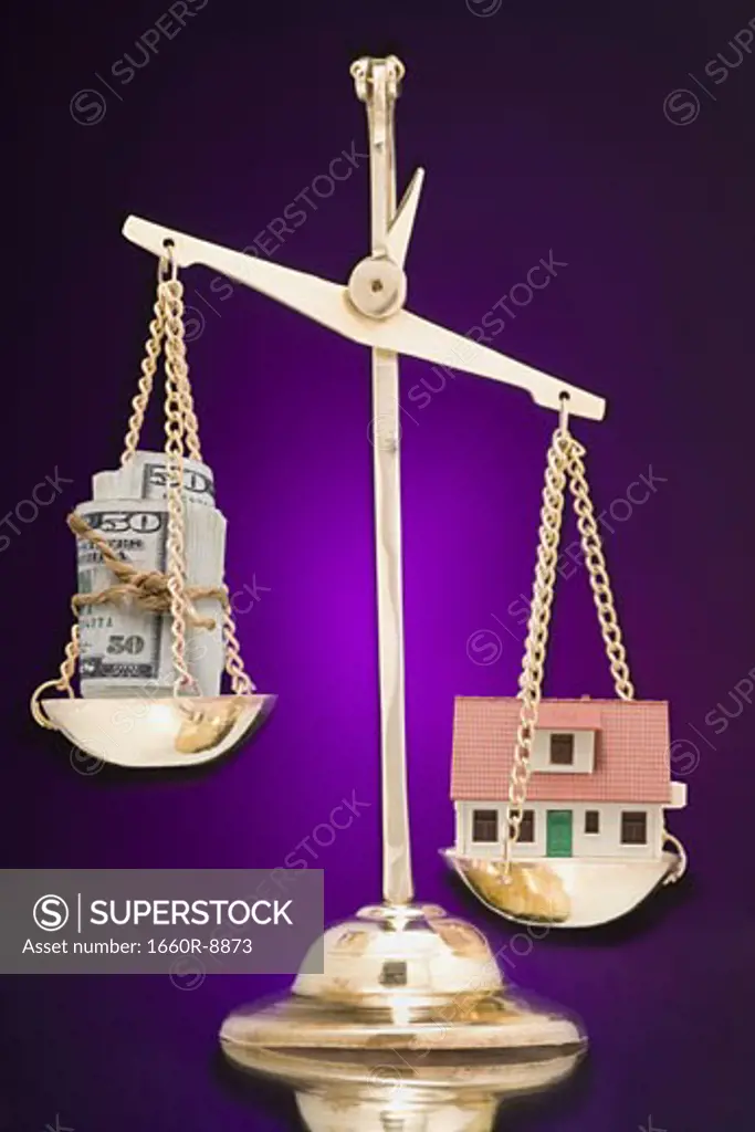 Paper currency and a model house on a weighing scale