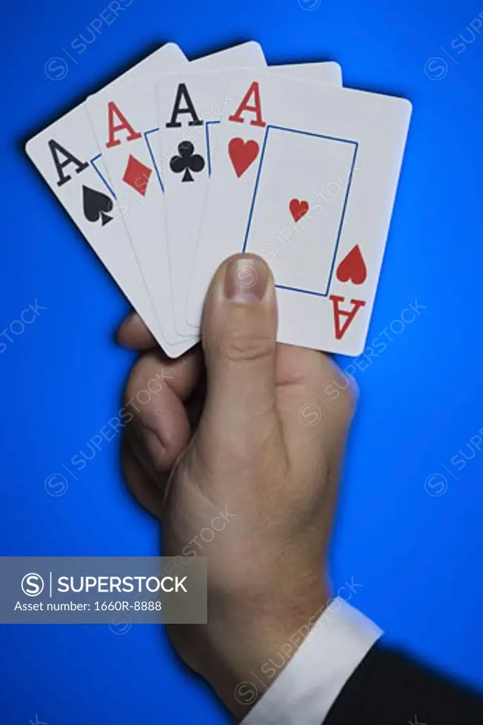 Close-up of a person's hand holding four aces