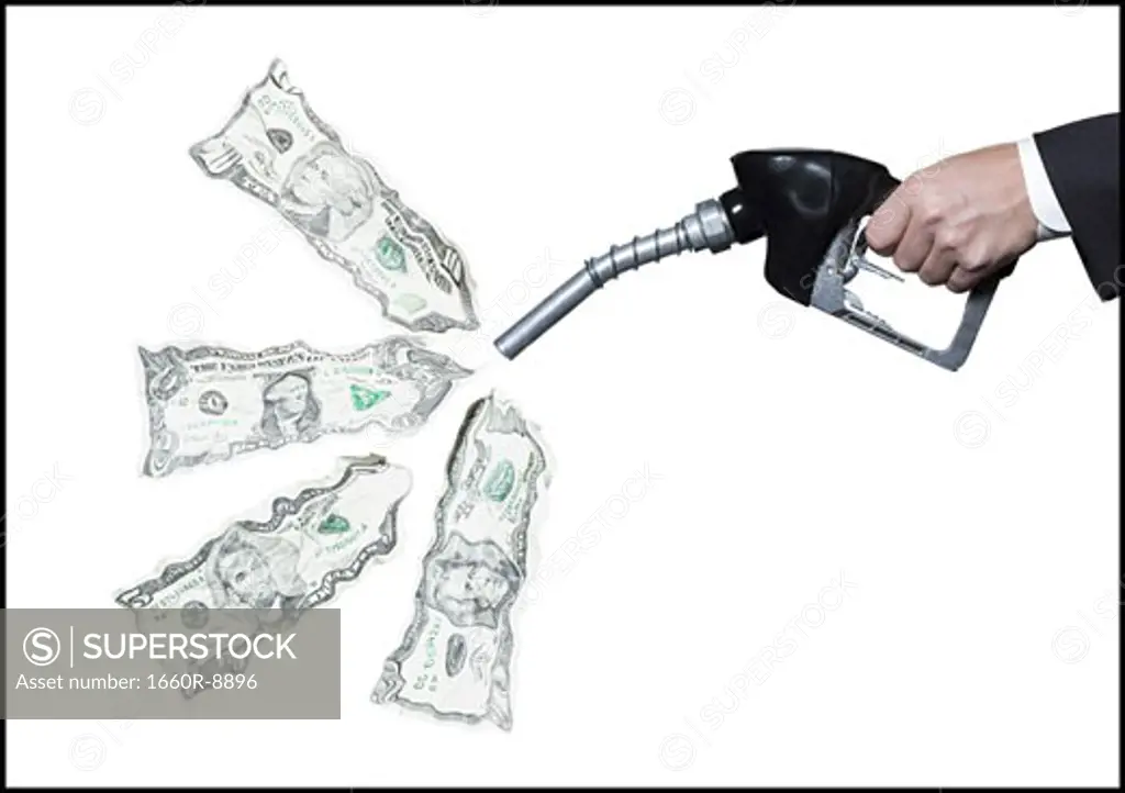 Close-up of a person's hand holding a fuel pump with dollar bills coming out of it