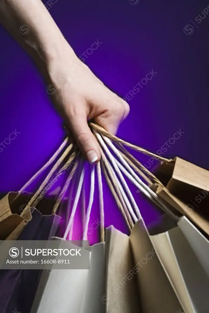 Close-up of a person's hand holding shopping bags