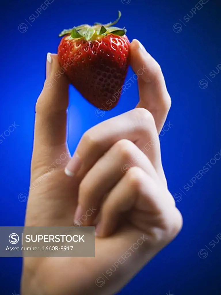 Close-up of a woman's hand holding a strawberry