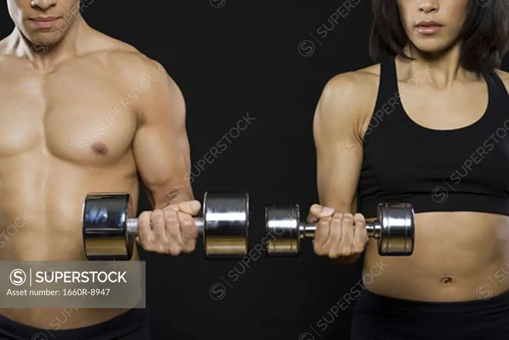Mid adult man and a young woman exercising with dumbbells
