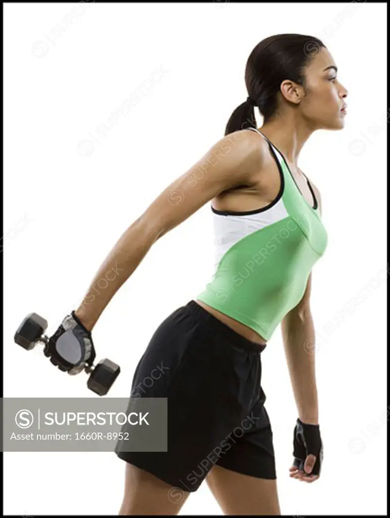 Profile of a young woman exercising with a dumbbell