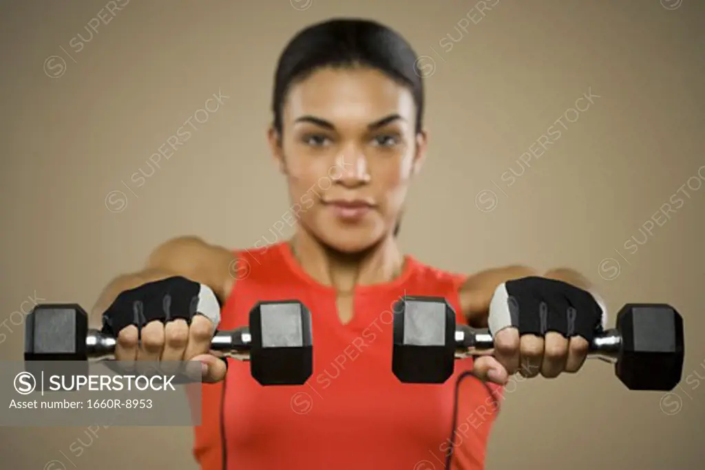 Portrait of a young woman exercising with dumbbells