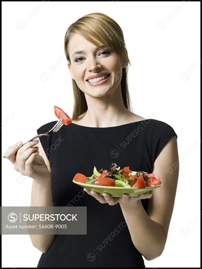 Portrait of a young woman holding a plate of salad and a fork