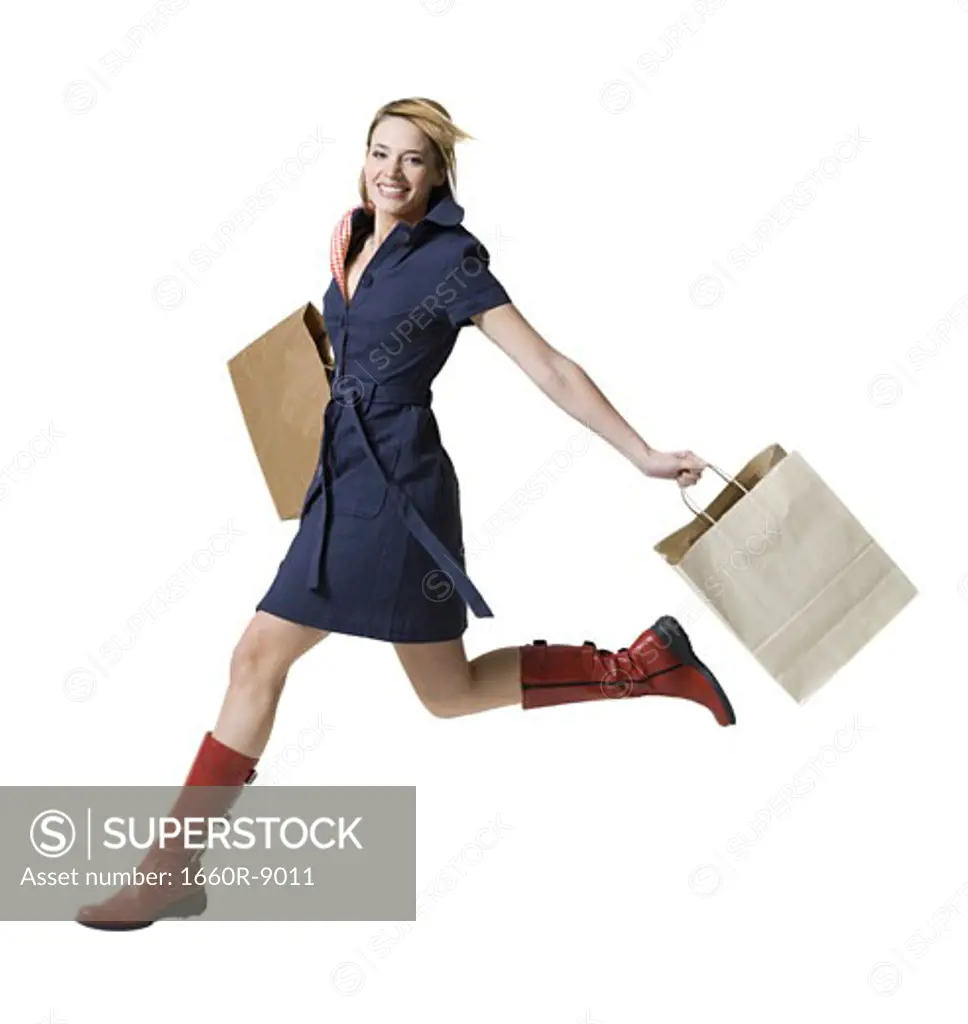 Portrait of a young woman jumping with shopping bags