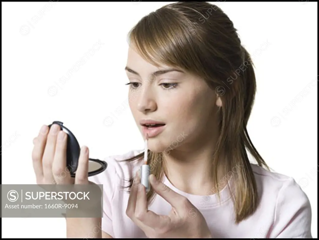 Close-up of a girl applying lipstick on her lips