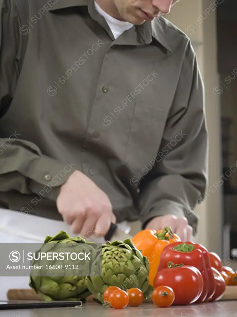 Close-up of a young man cutting vegetables