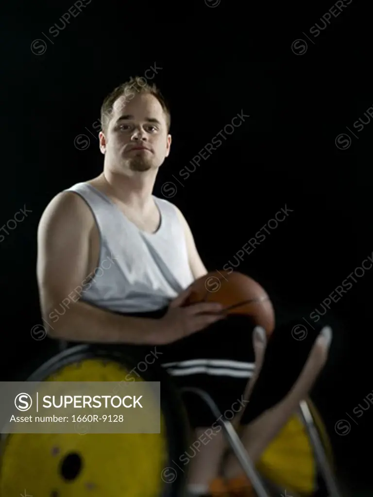 Close-up of a young man sitting in a wheelchair holding a basketball