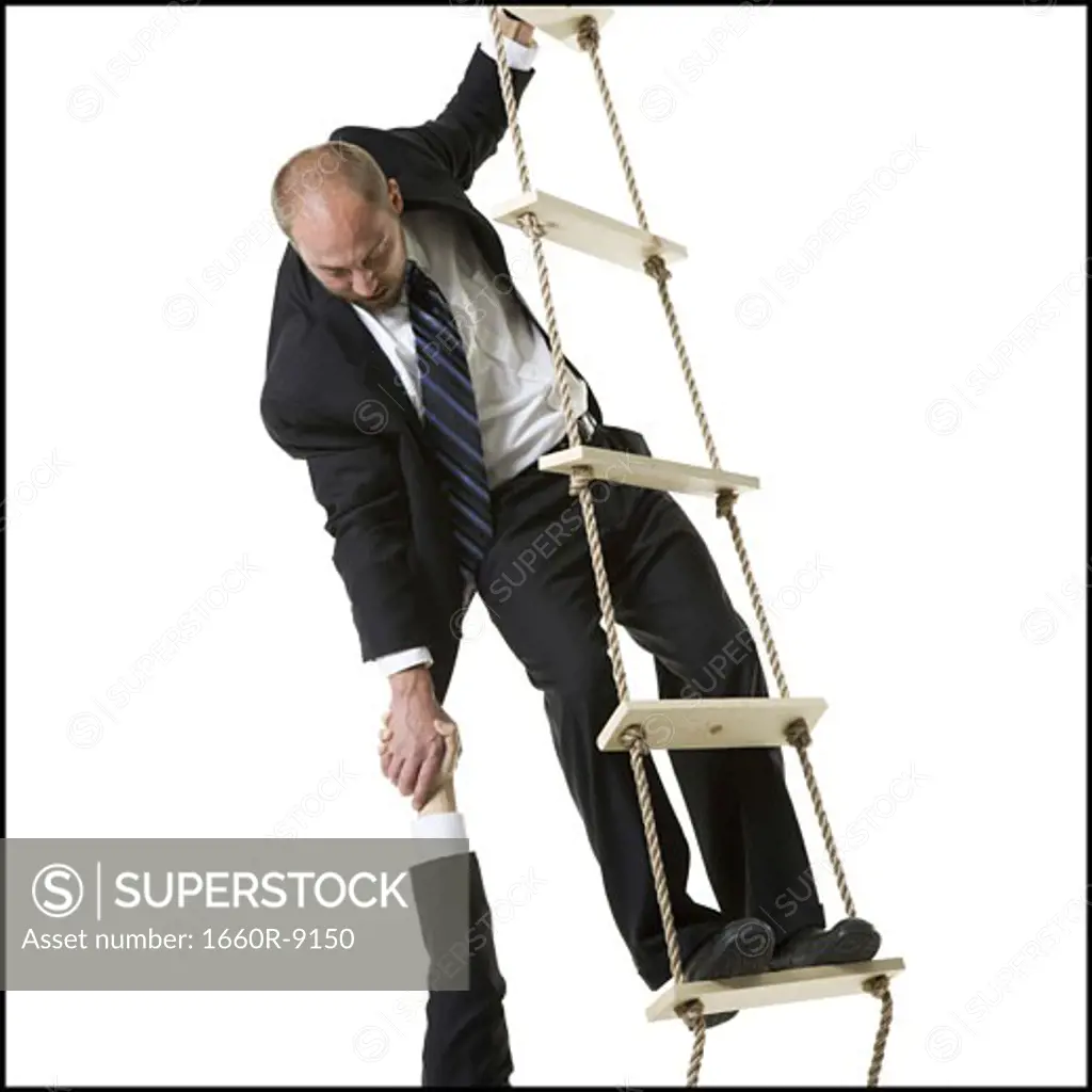 Close-up of a businessman helping a person climb a ladder