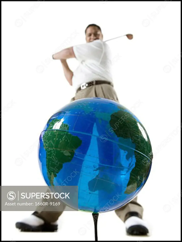 Low angle view of a mid adult man hitting a globe with a golf club