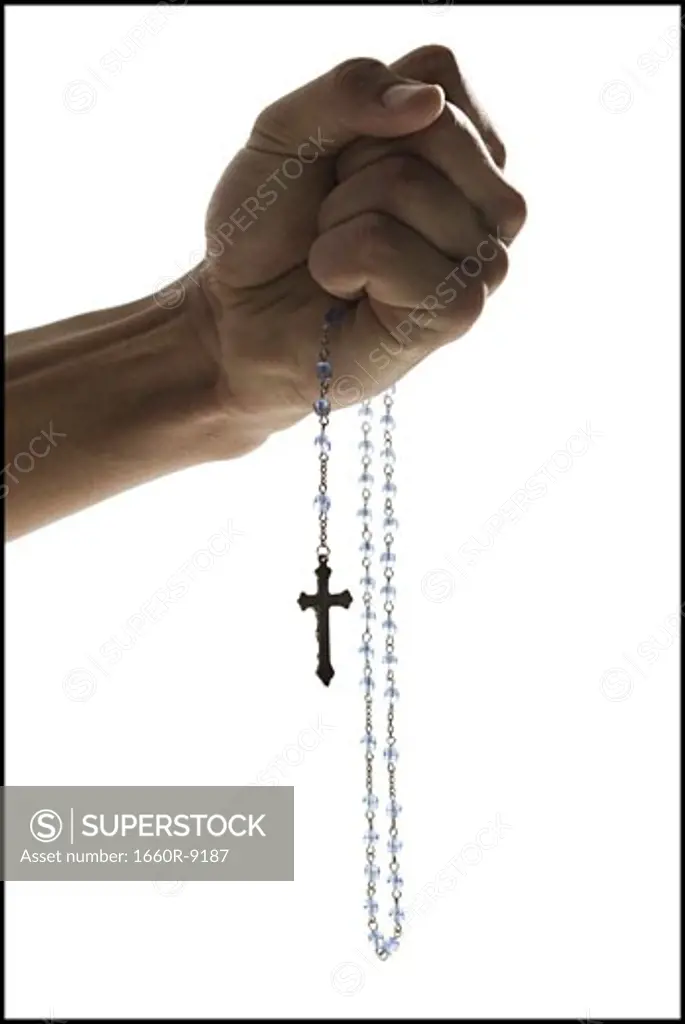 Close-up of a young man's hand holding a crucifix