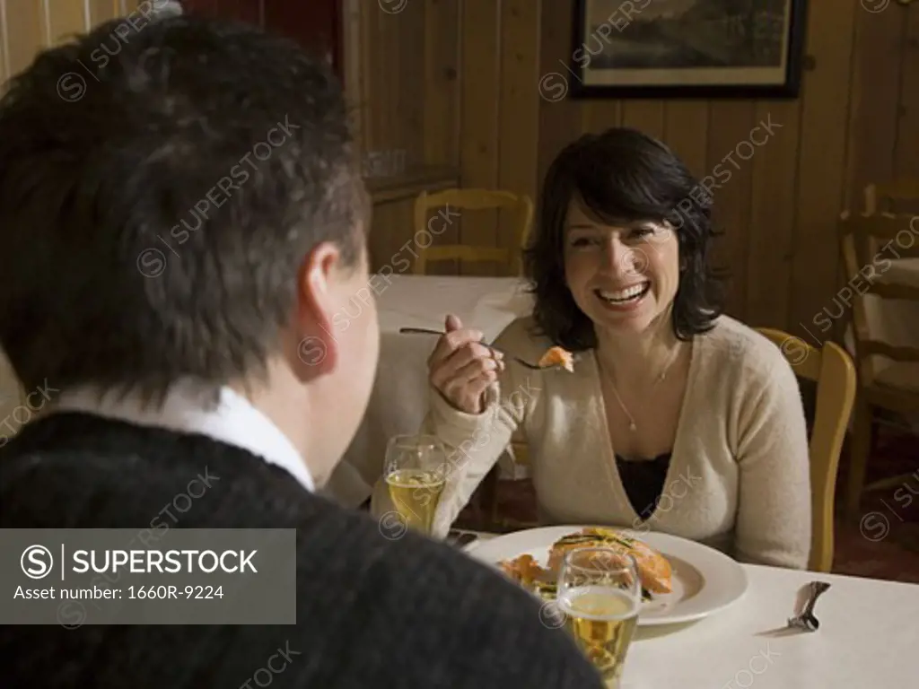 Mid adult woman eating food in front of a mid adult man