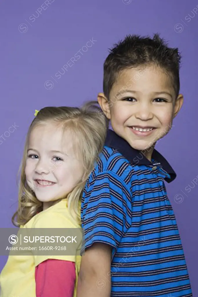 Portrait of a girl and a boy standing back to back