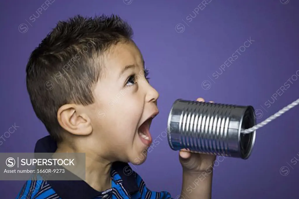 Close-up of a boy shouting into a tin can phone