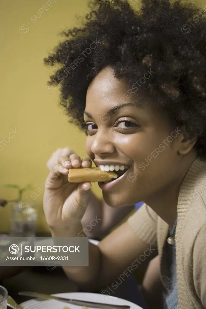 Portrait of a young woman eating a spring roll
