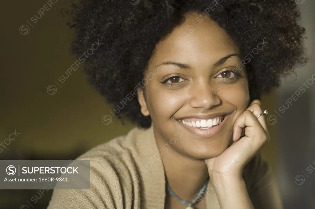 Portrait of a young woman smiling with her hand on her chin