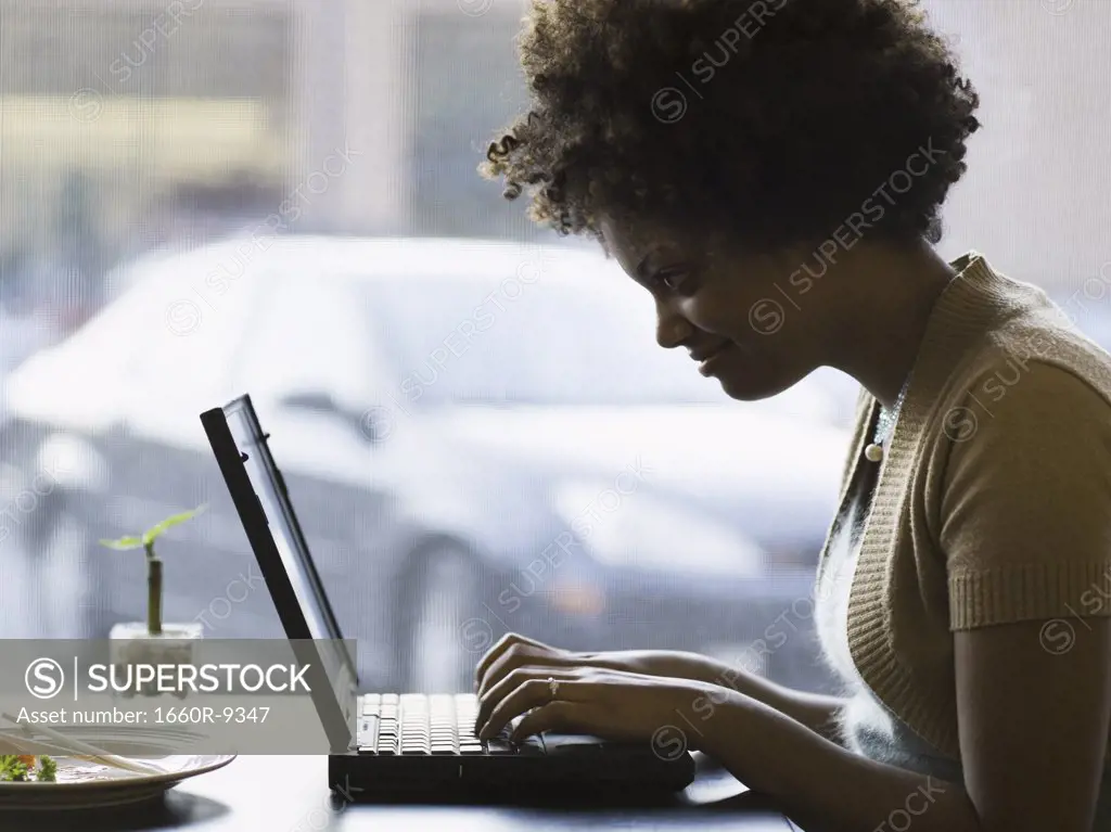 Profile of a young woman working on a laptop