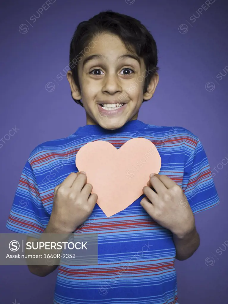 Portrait of a boy holding a heart shaped paper cutout