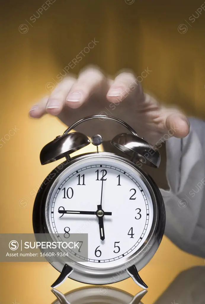Close-up of a person's hand reaching out for an alarm clock