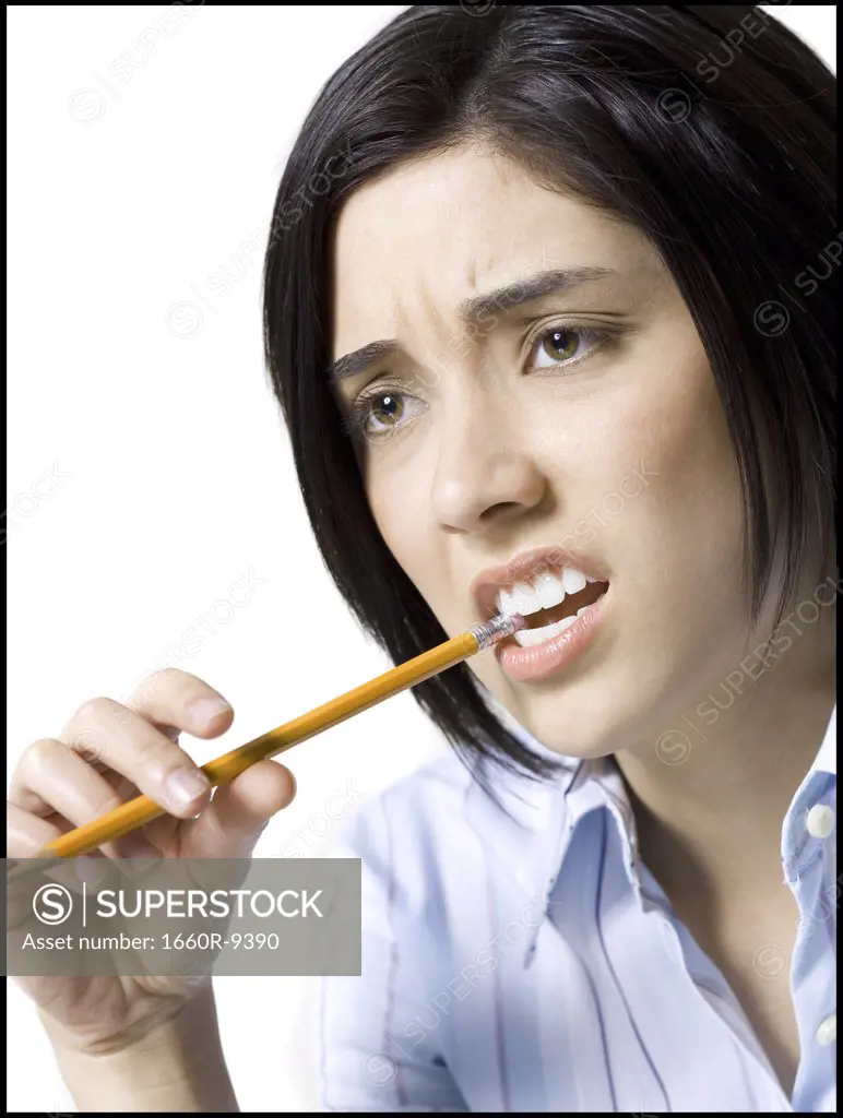 Close-up of a young woman biting a pencil