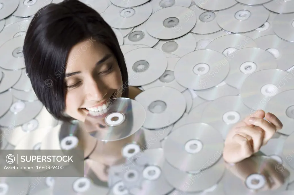 High angle view of a young woman biting a CD