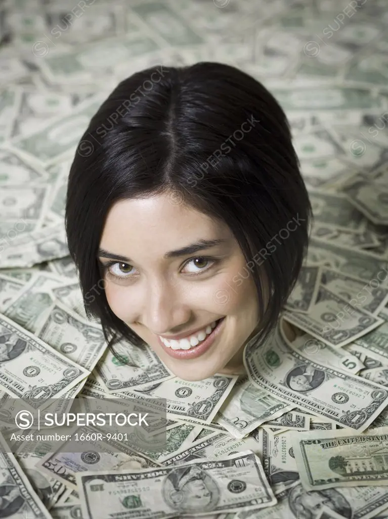 Portrait of a young woman buried under a heap of paper money
