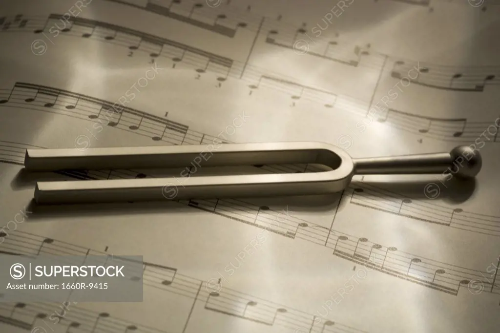 Close-up of a tuning fork and music sheets