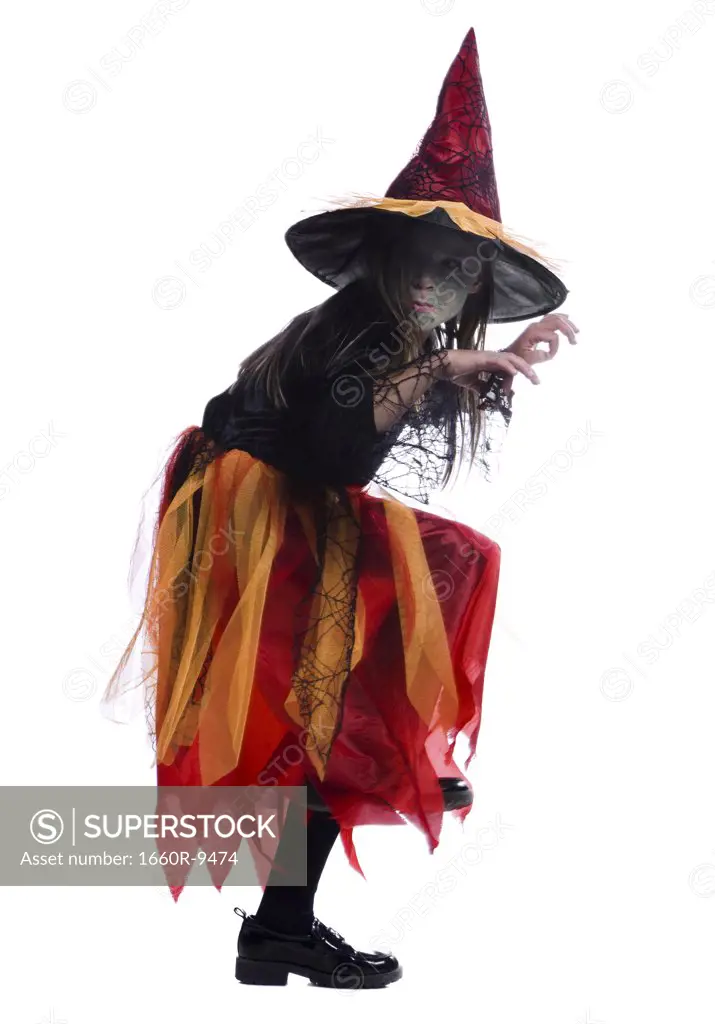Profile of a girl wearing a witch costume and standing on one leg