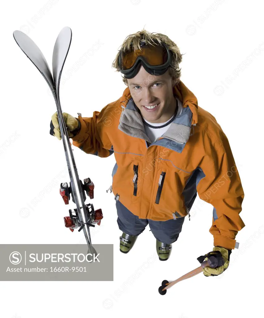 High angle view of a young man holding skis and a ski pole