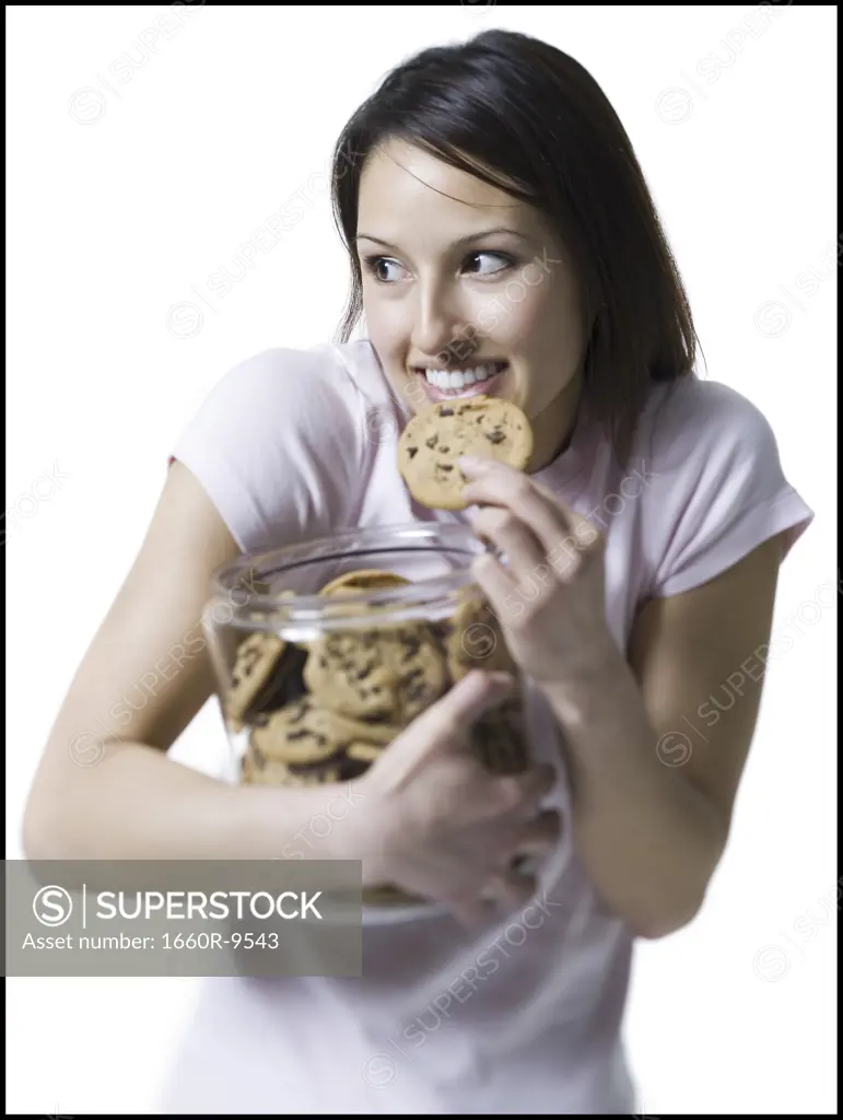 Close-up of a young woman eating a cookie out of a jar of cookies