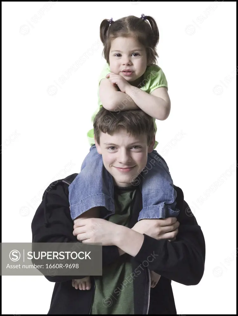 Portrait of a teenage boy carrying his sister on his shoulders