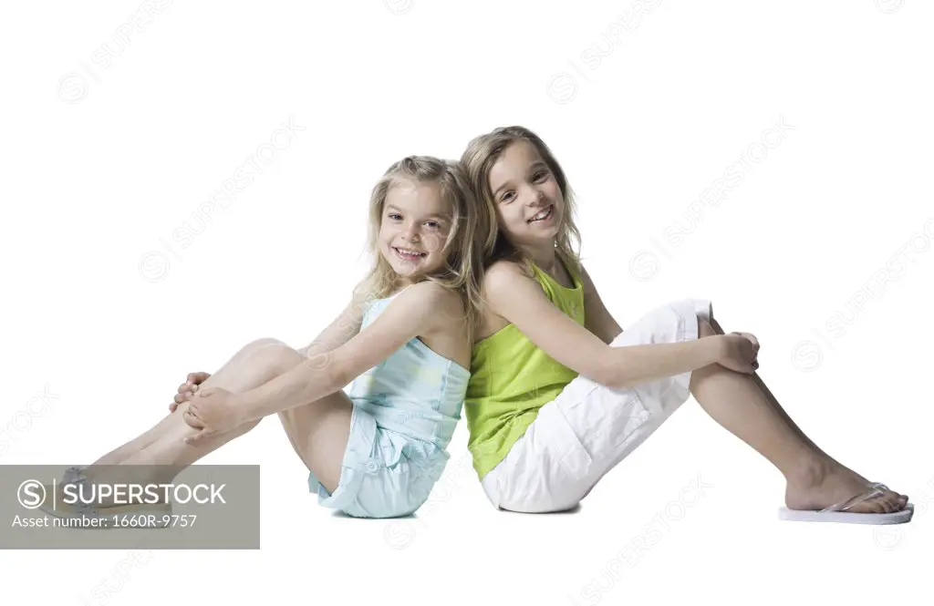 Portrait of two sisters sitting back to back