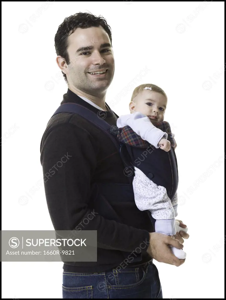 Portrait of a mature man carrying his son in a harness
