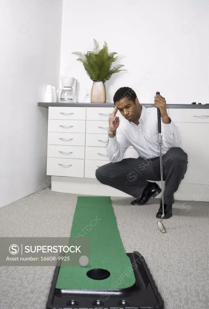 Mid adult man practicing golf in the office
